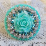 Bague Blue Flowers brodée avec un cabochon en forme de rose en résine, chaîne strass Cristal, toupies Jet de haute qualité AB2X et farfalles ovales. Les couleurs sont : l’Argenté et le Vert Menthe